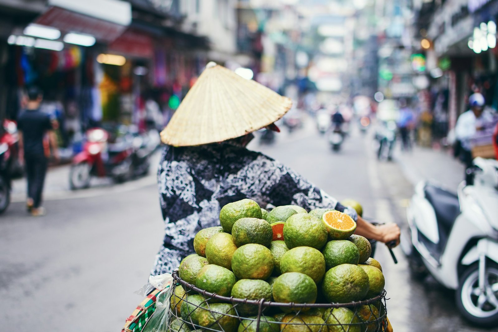 City life in street of old quarter in Hanoi. Fruit seller in traditional conical hat.