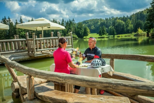 Couple biker dining outdoors on a lake after a bike tour around Lake Bloke in Nova Vas, Slovenia