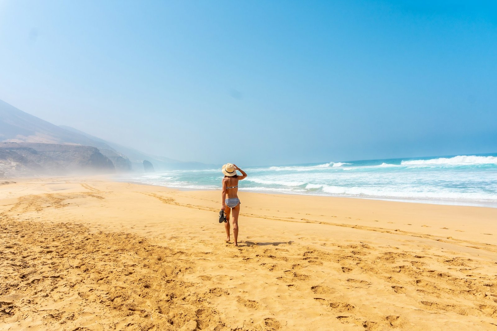 A young woman on the wild beach Cofete of the natural park of Jandia, Fuerteventura
