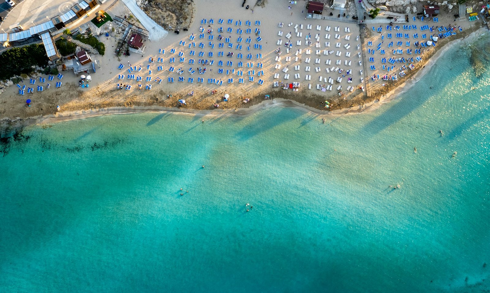 Beach umbrellas in a row at fig tree bay beach Protaras Cyprus. Summer vacations holiday resort