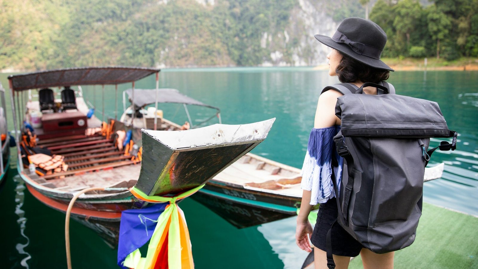 A female backpacker waiting for a long tail boat at the pier.