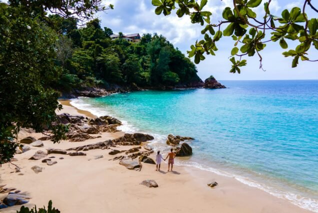 Couple of men and women relaxing at Banana beach with palm trees in Phuket Thailand