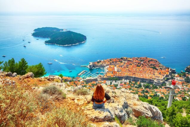 Happy girl enjoys view of old town (medieval Ragusa) and Dalmatian Coast