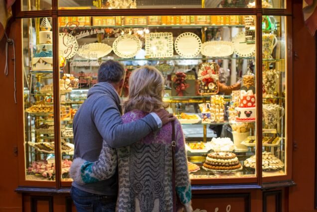 Rear view of romantic mature couple at cake shop window, Majorca, Spain